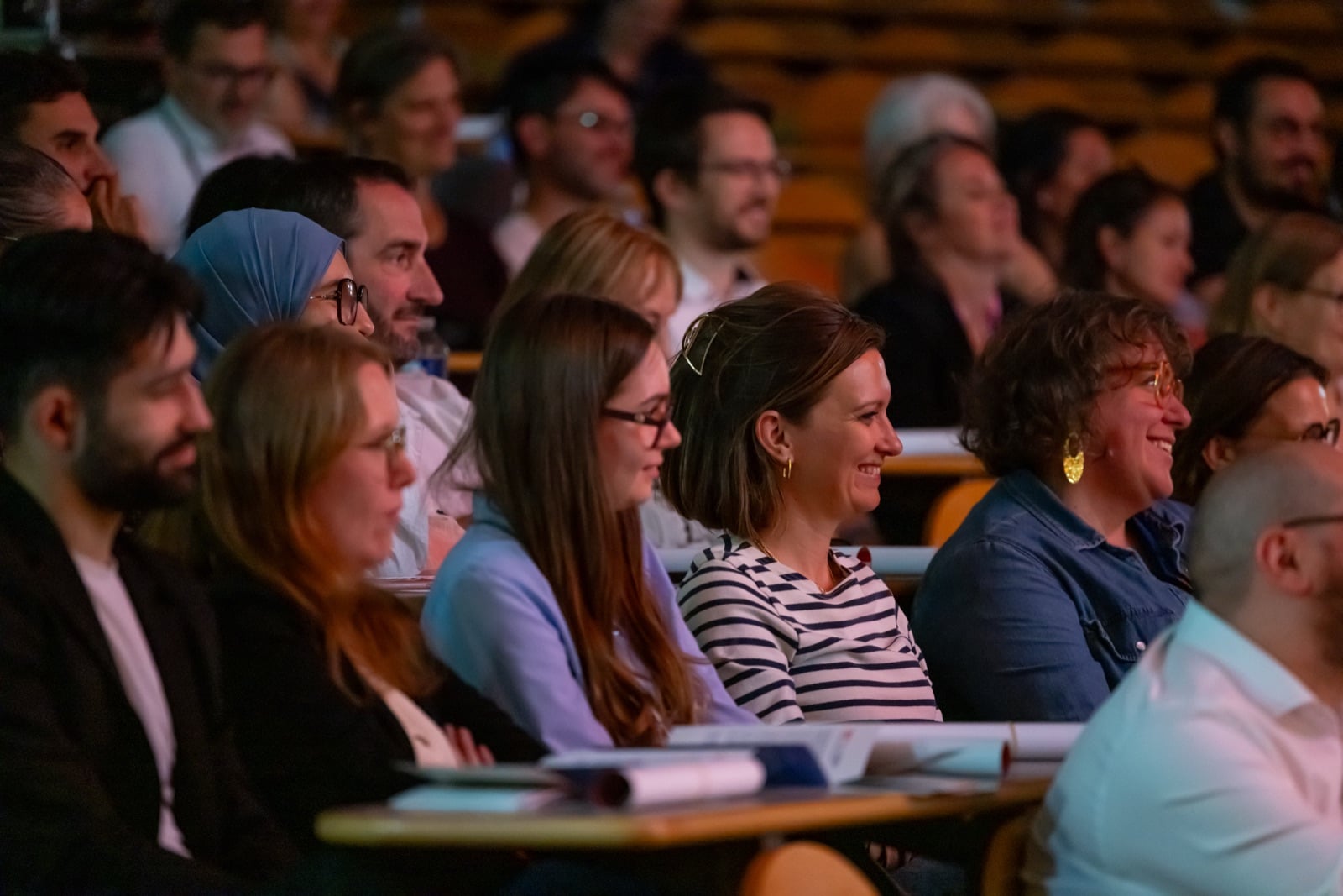 Audience members laughing in a raked lecture theatre during a TEDx salon